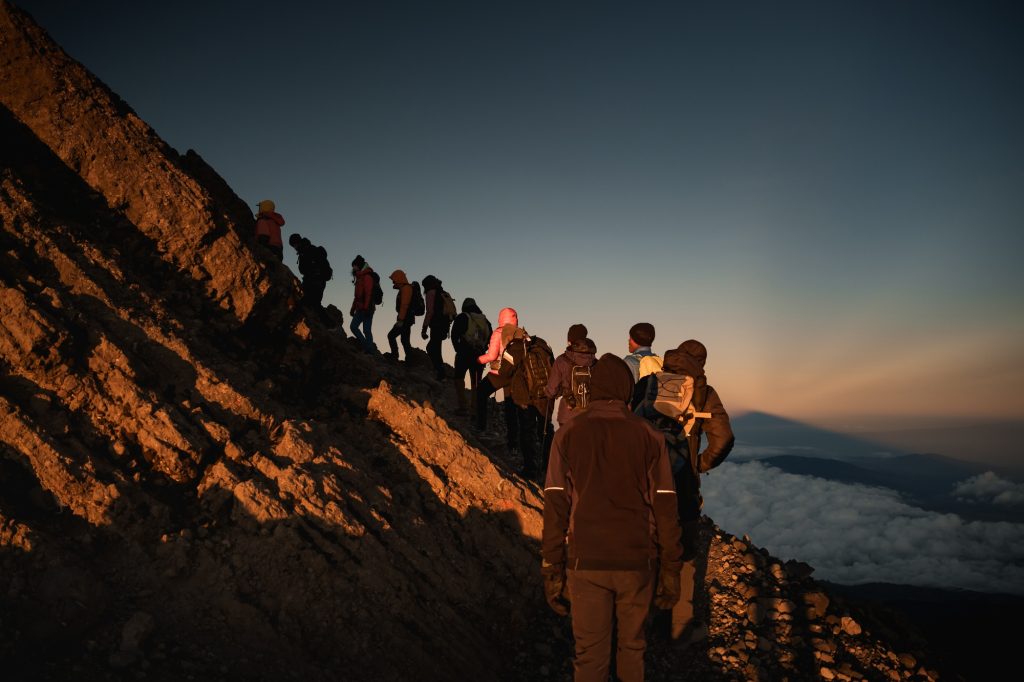 Mountaineers reaching mount meru summit at sunrise, tanzania, africa